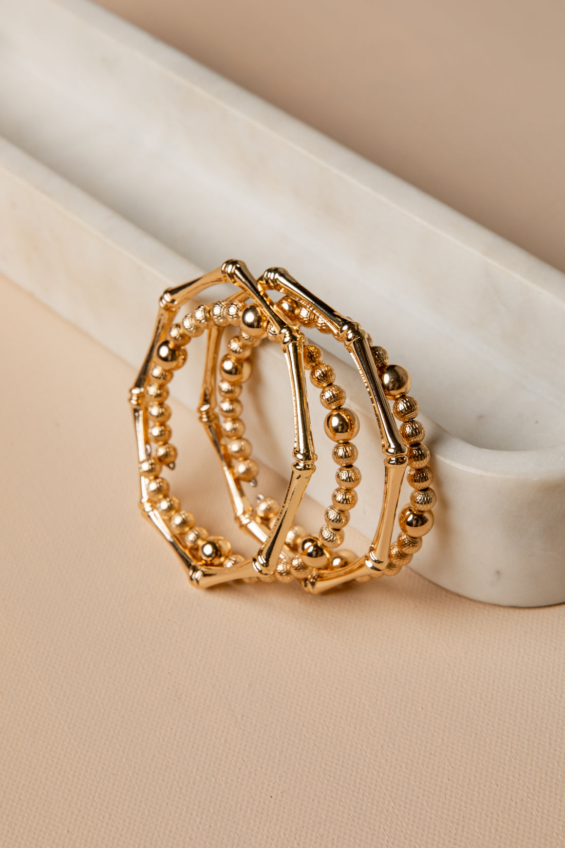 Gold ring with beaded design on a beige surface