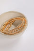 Three gold beaded bracelets on a white dish with a white background