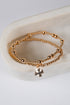 Gold beaded bracelet with a cross charm on a white surface