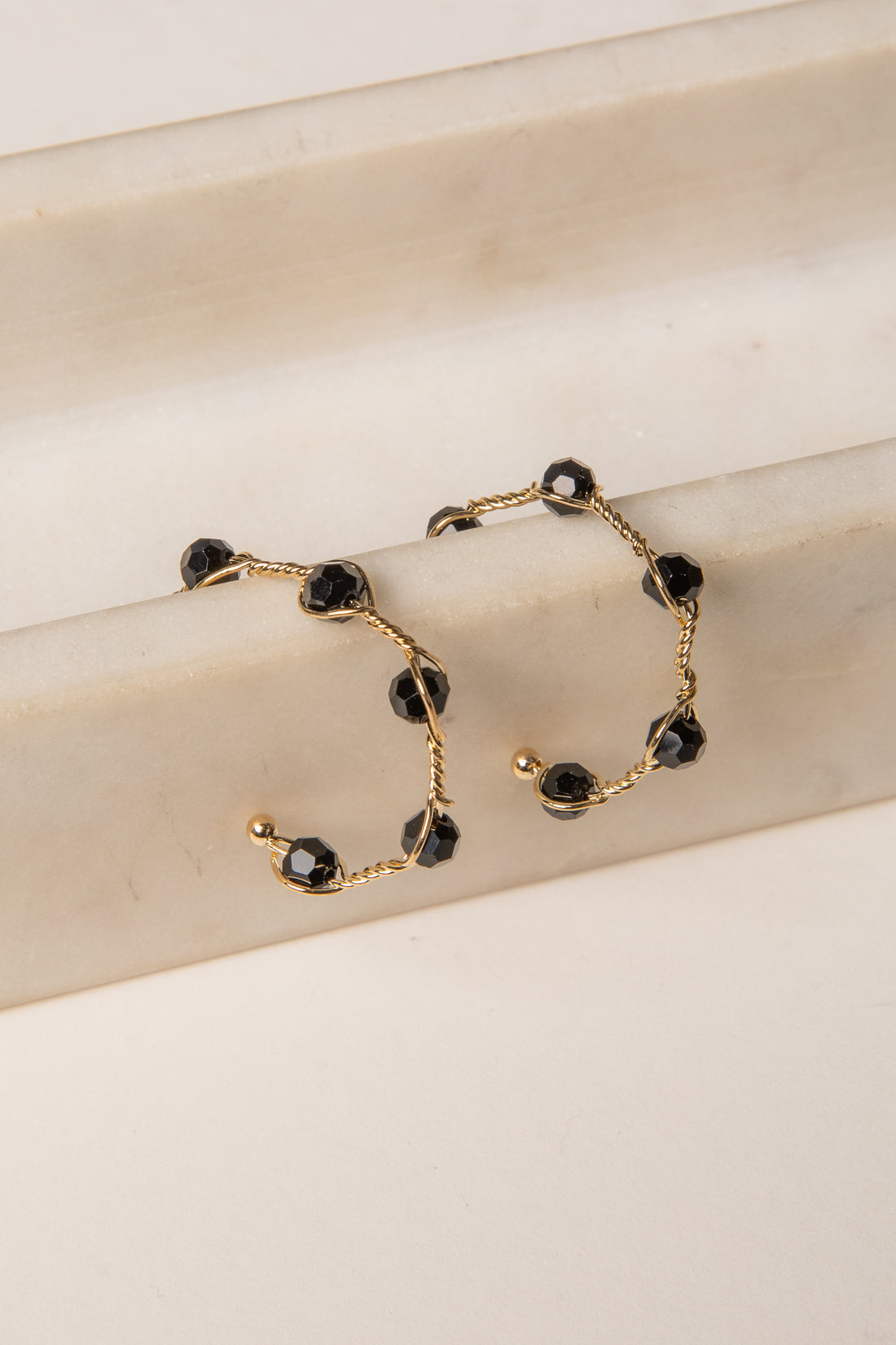 Gold bracelet with black beads on a beige surface