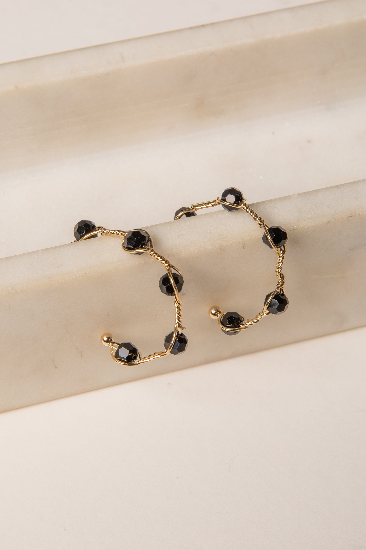 Gold bracelet with black beads on a beige surface