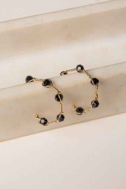 Gold bracelet with black beads on a beige surface