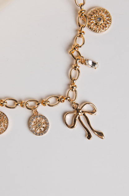 Gold bracelet with various charms on a light gray background
