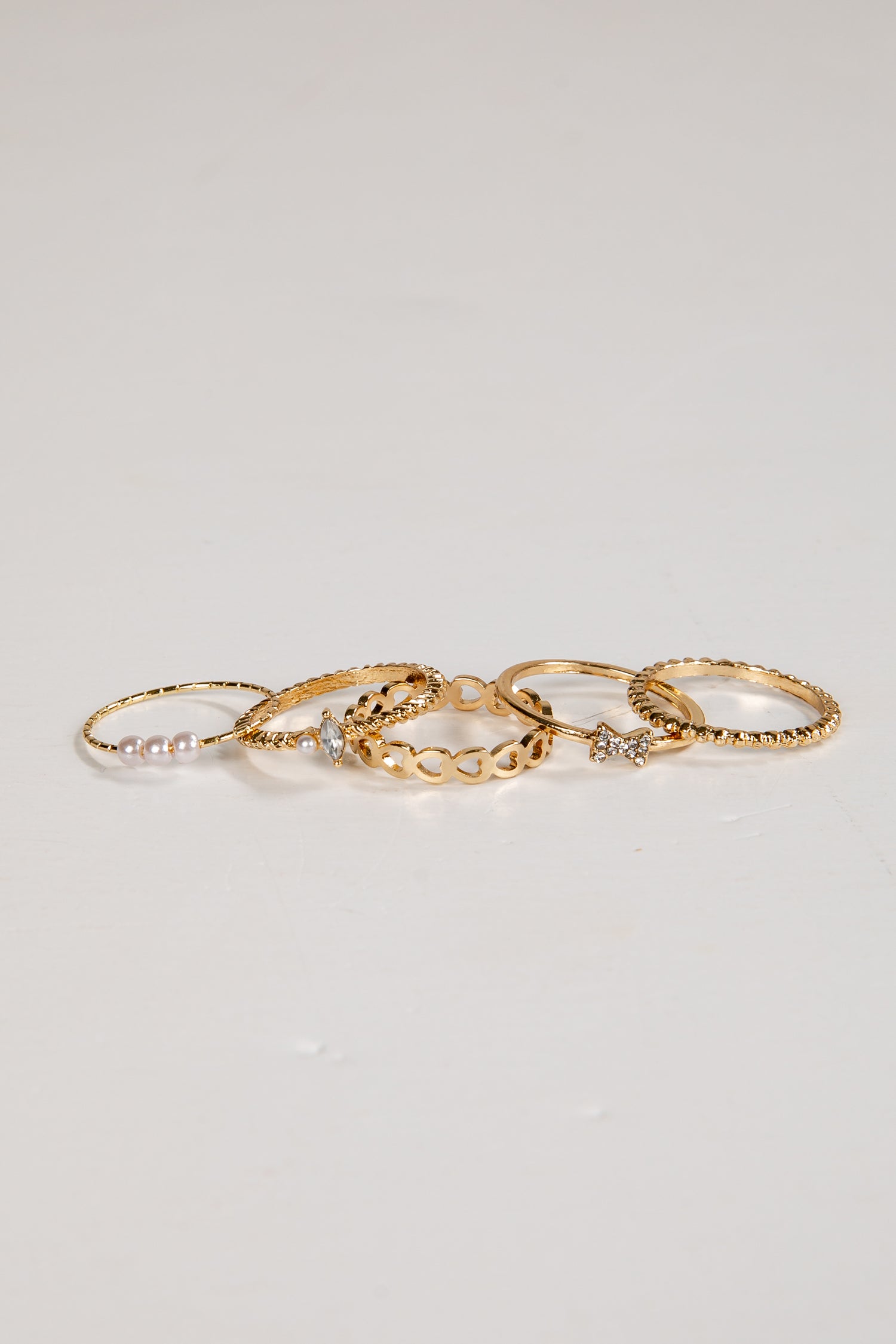 Set of gold rings with small stones on a light gray background