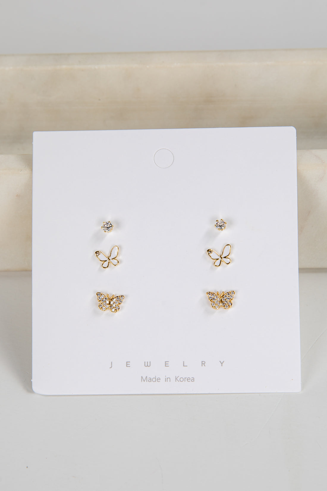 Set of butterfly-shaped earrings on a white card with &