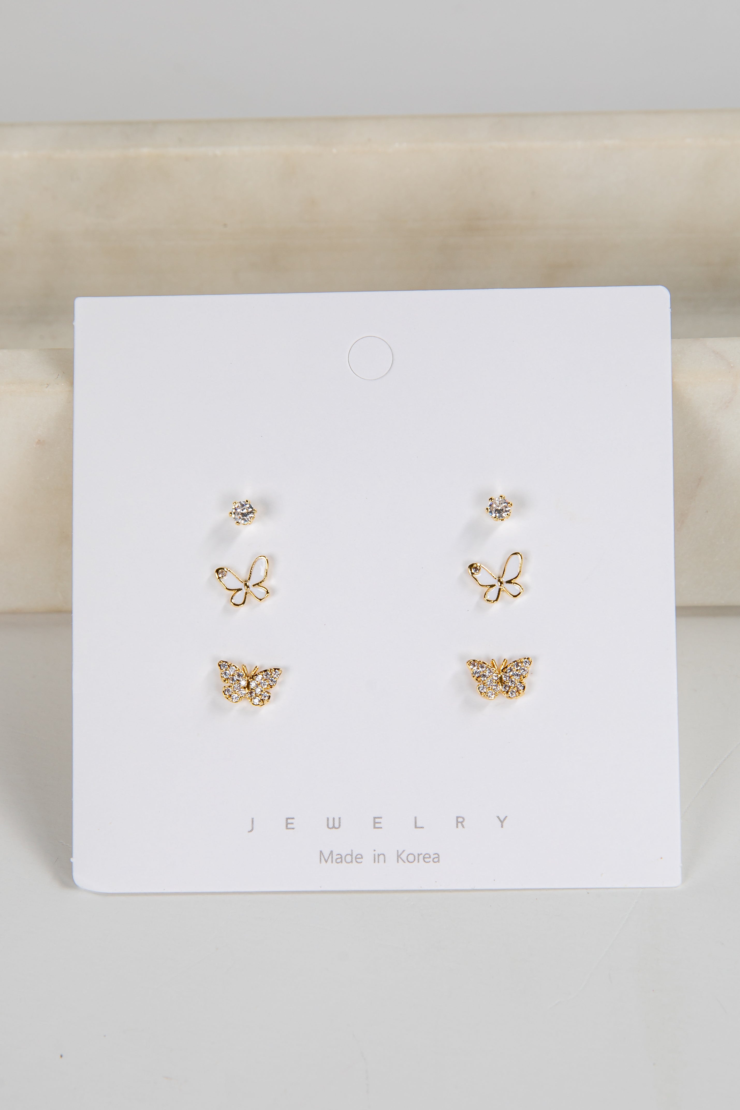 Set of butterfly-shaped earrings on a white card with &