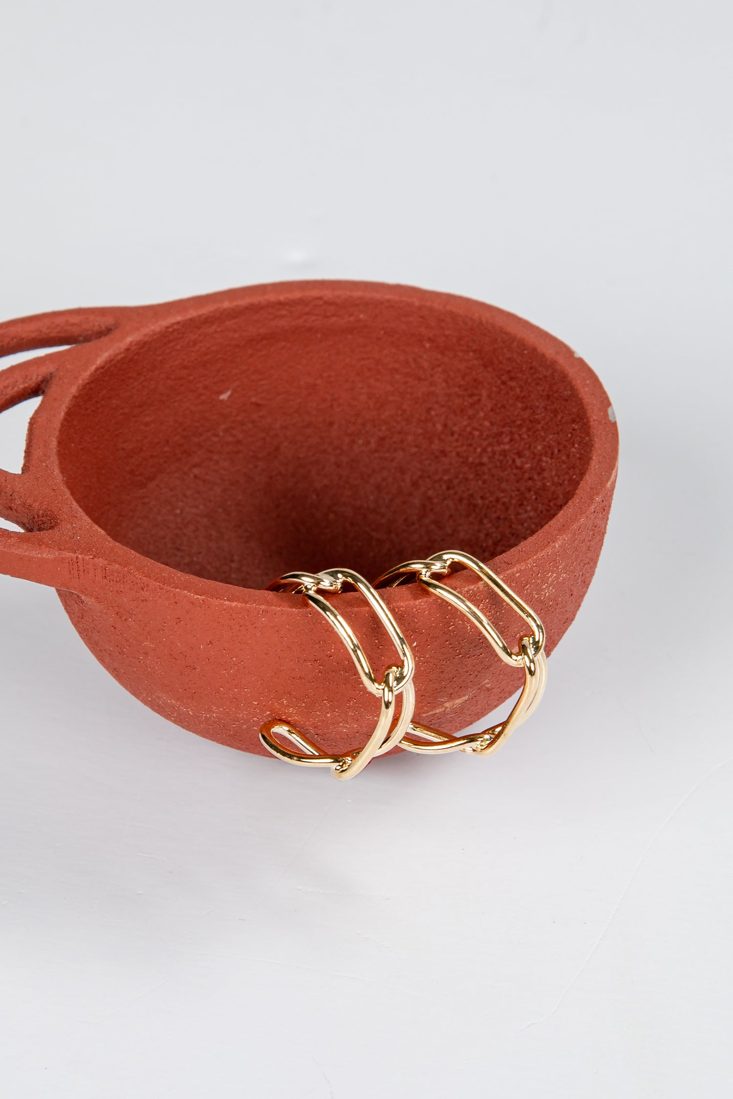 Terracotta bowl with gold chain on a white background