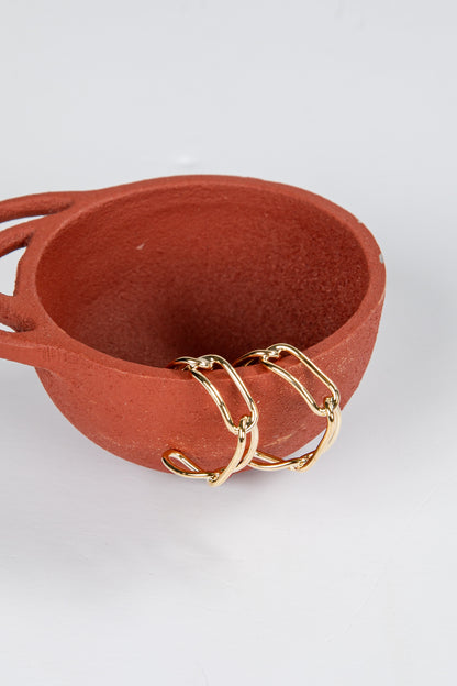 Terracotta bowl with gold chain on a white background