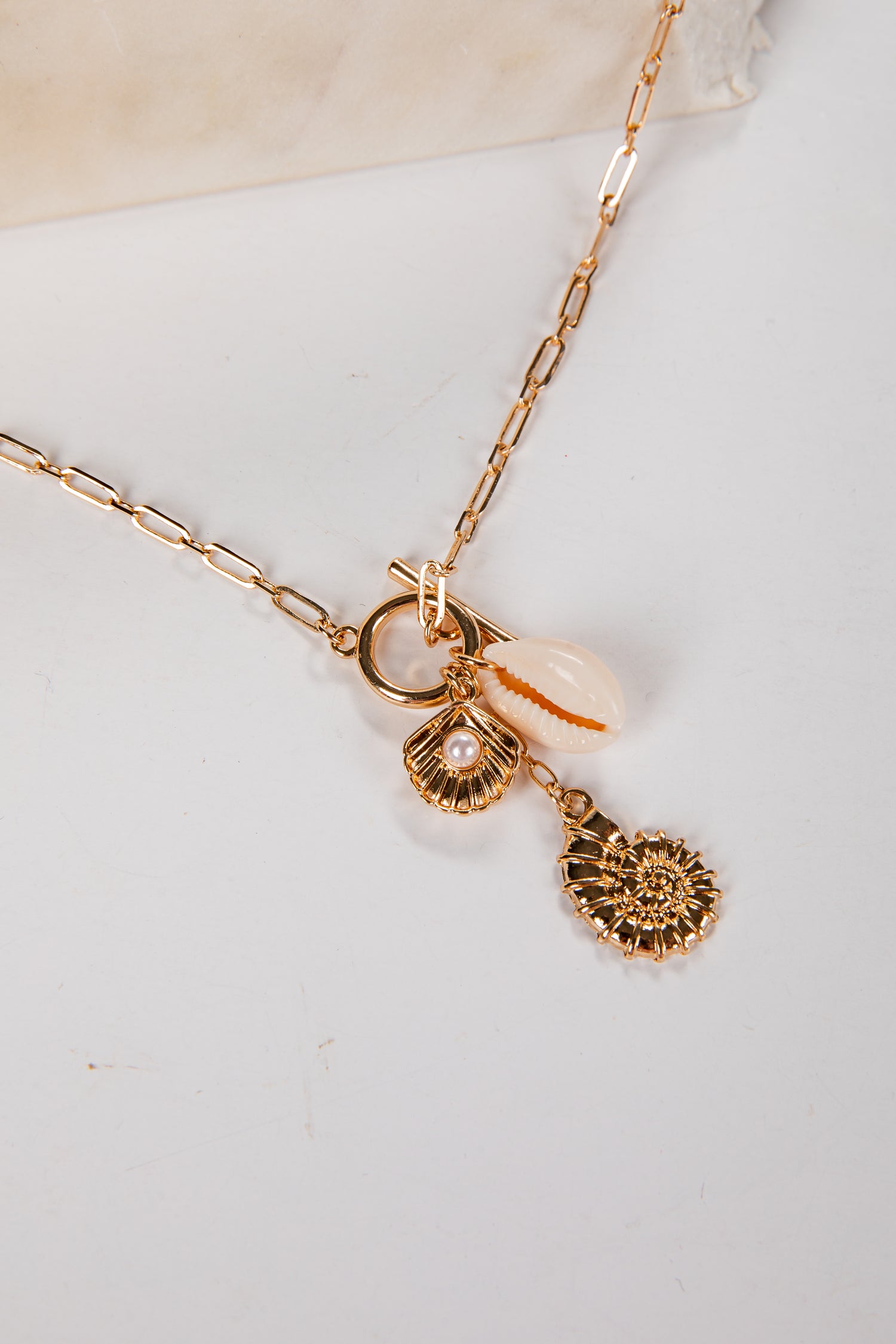 Gold necklace with charms on a white surface