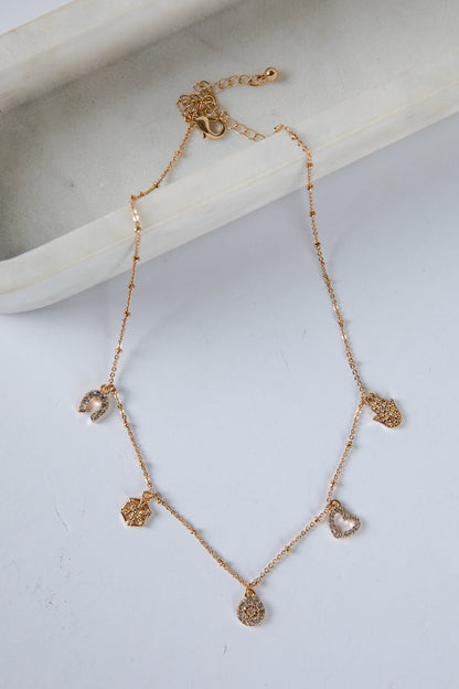 Gold necklace with heart-shaped pendants on a light gray surface