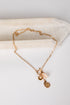 Gold necklace with charms on a white surface