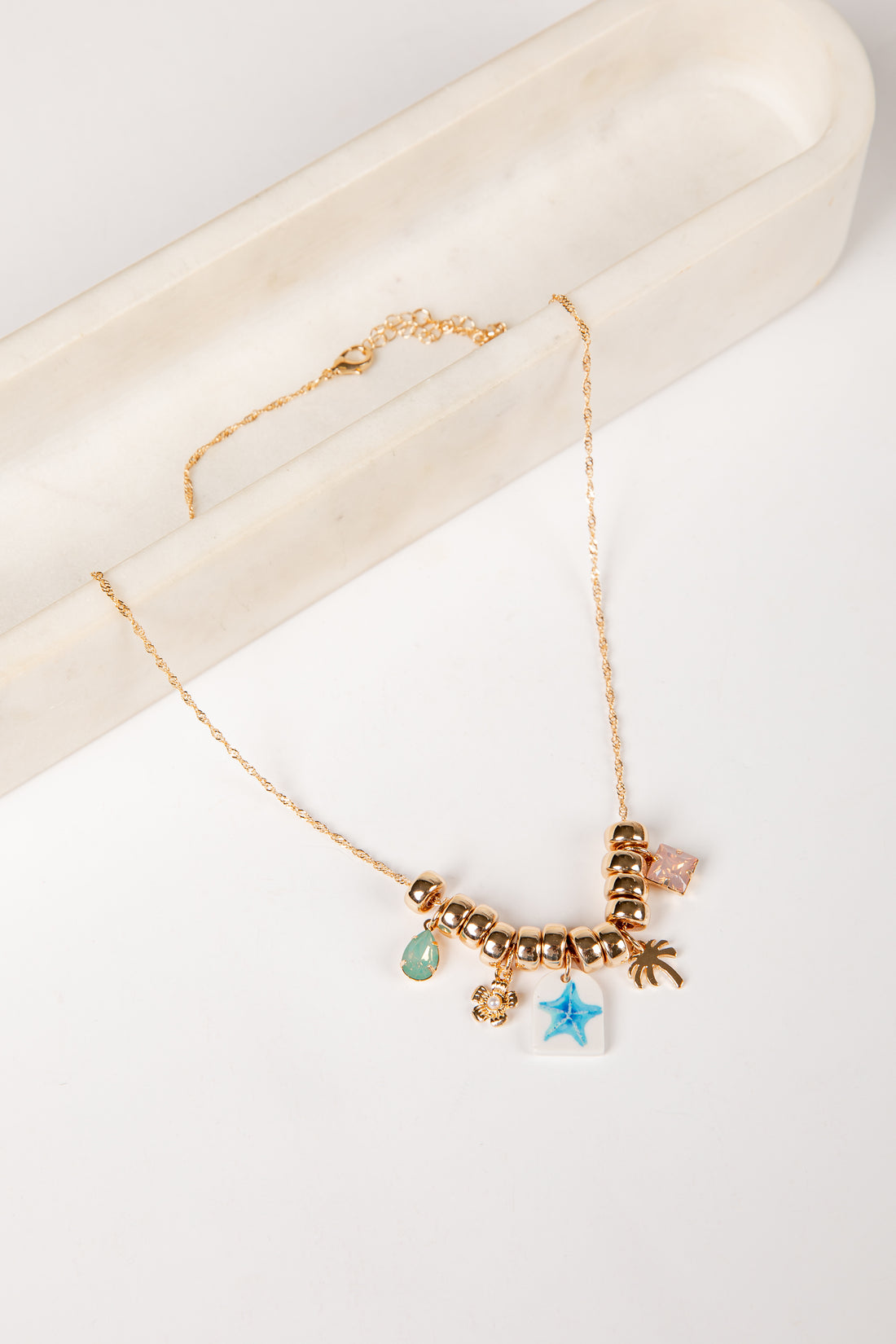 Gold necklace with charms on a white surface