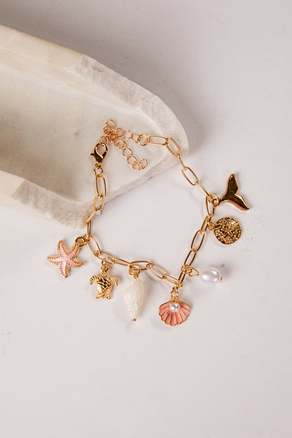 Gold bracelet with various charms on a light background