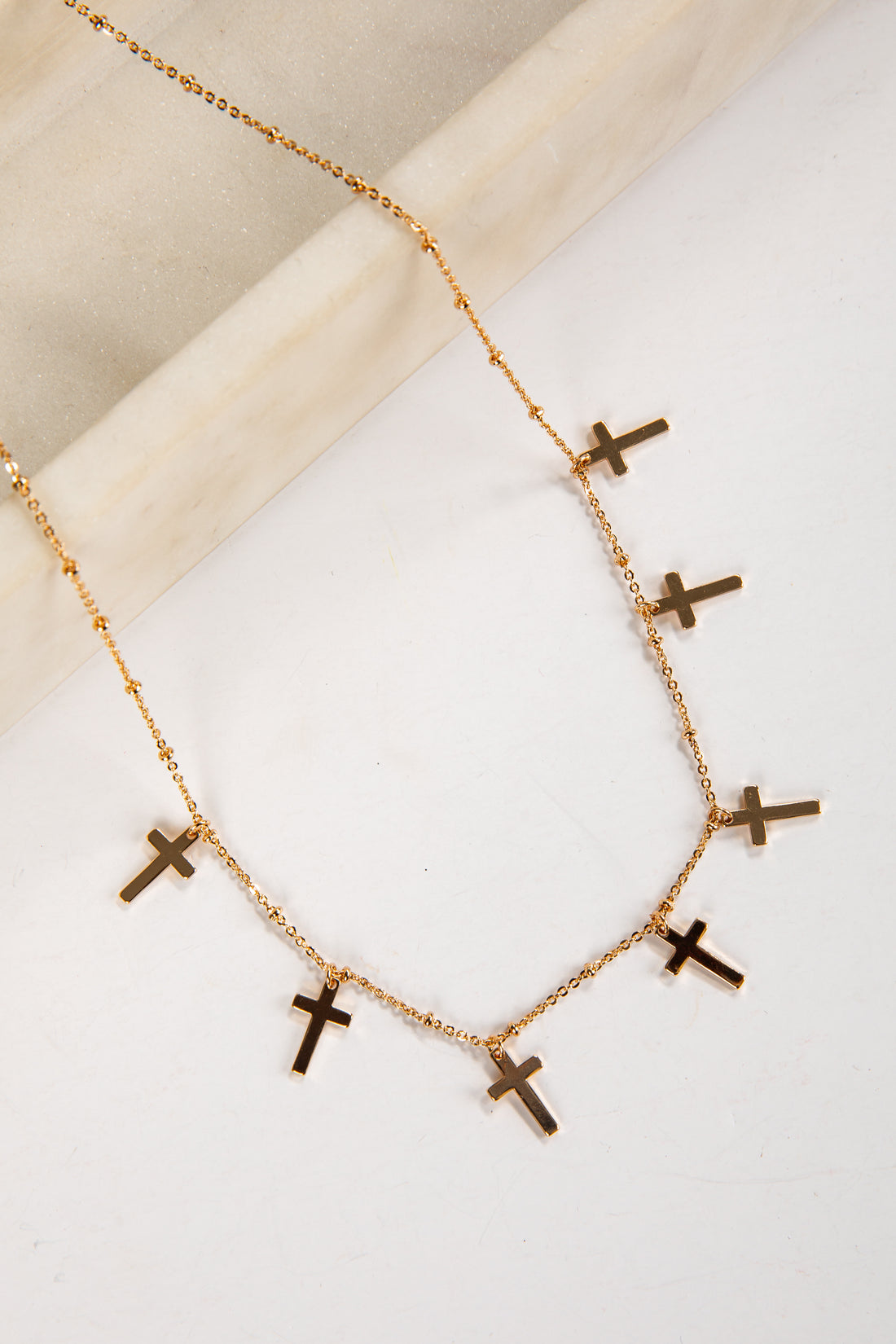 Gold necklace with cross pendants on a light background