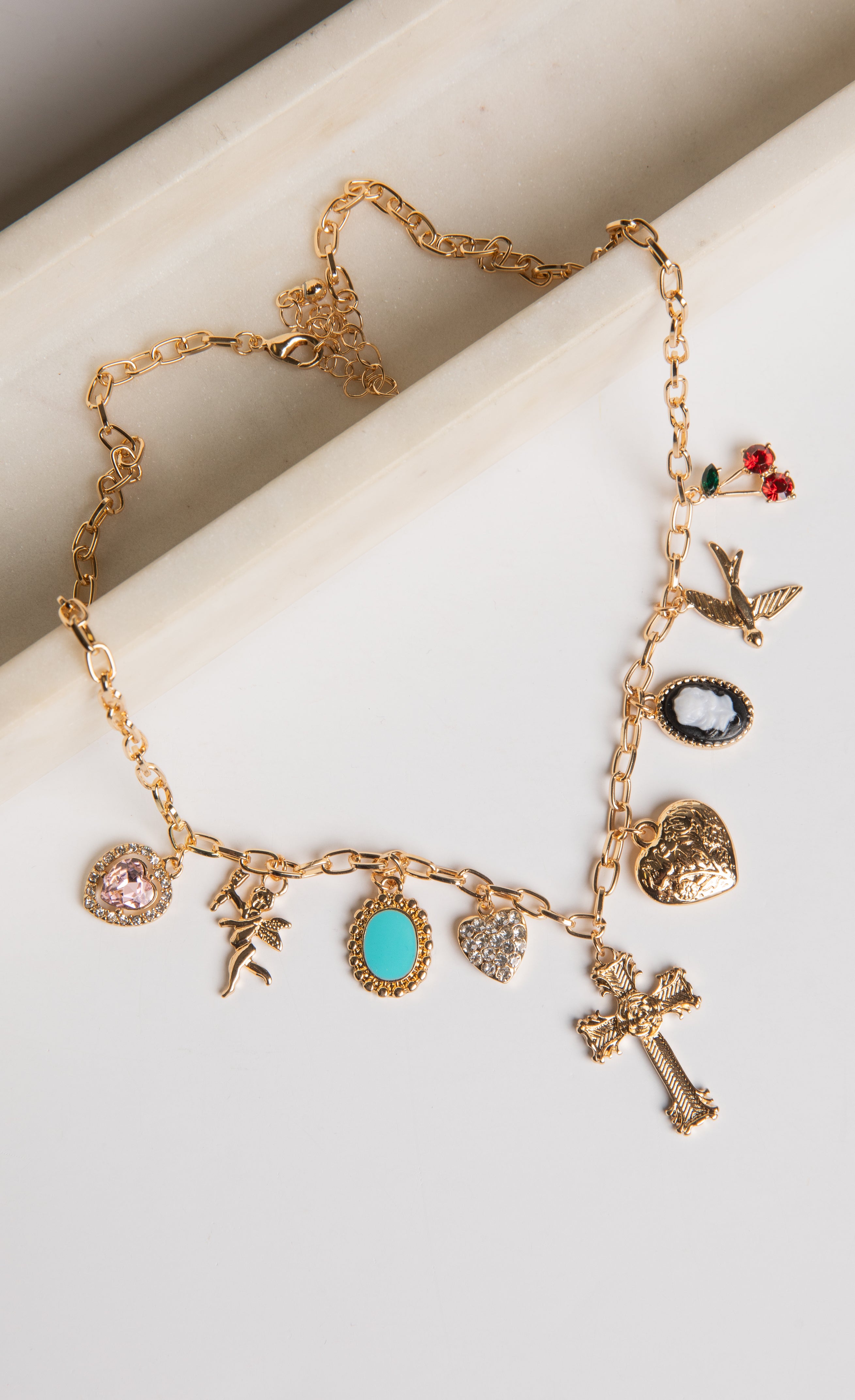 Gold necklace with various charms on a white surface