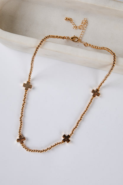 Gold necklace with cross pendants on a light background