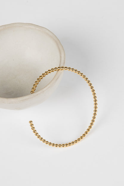 Gold beaded bracelet on a white surface