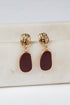 Gold and burgundy earrings on a marble surface