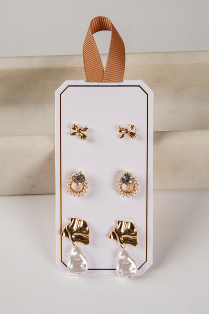 Set of earrings on a white card with a brown ribbon, against a light background