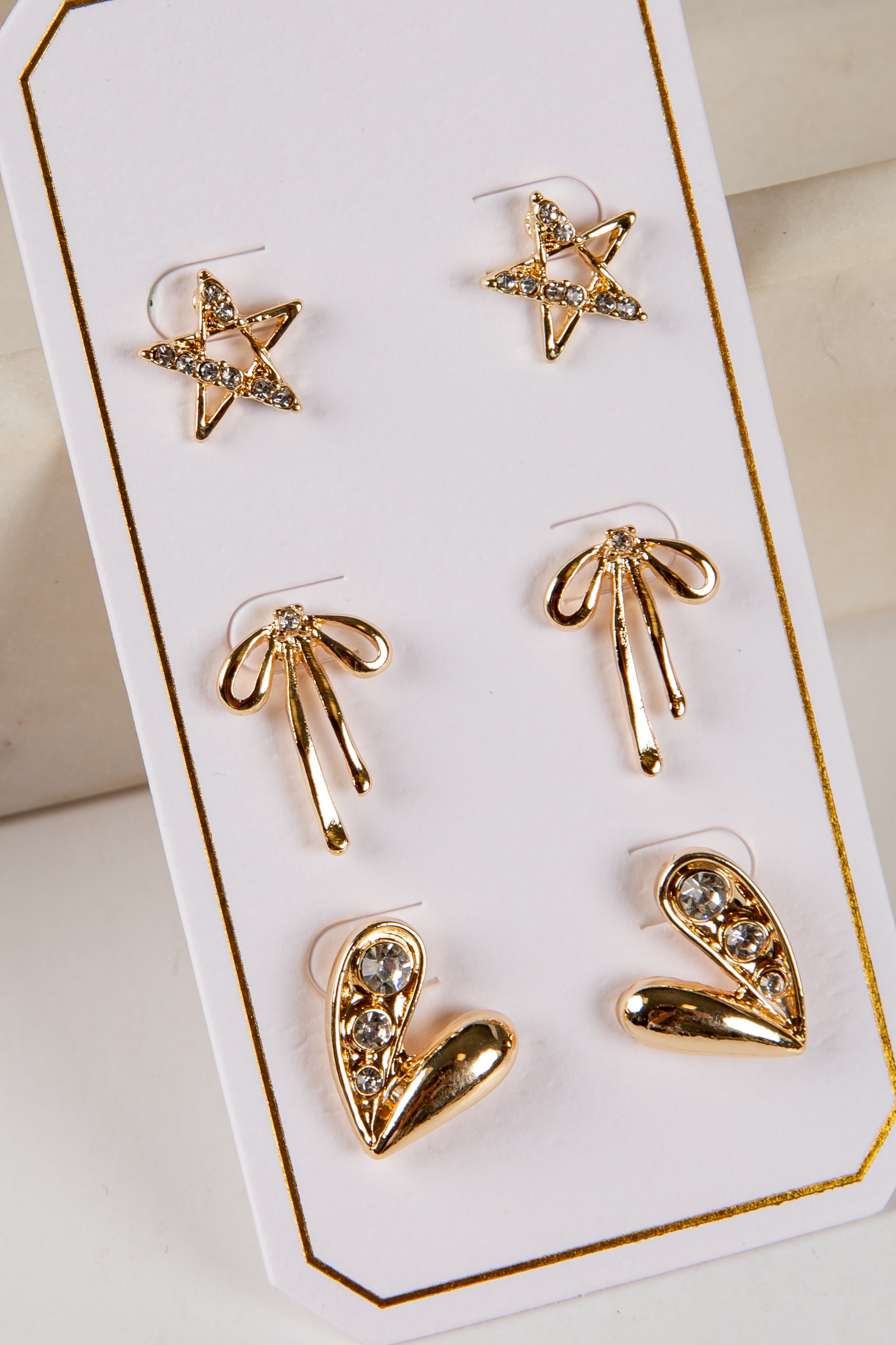 Set of gold earrings on a display card with a white background