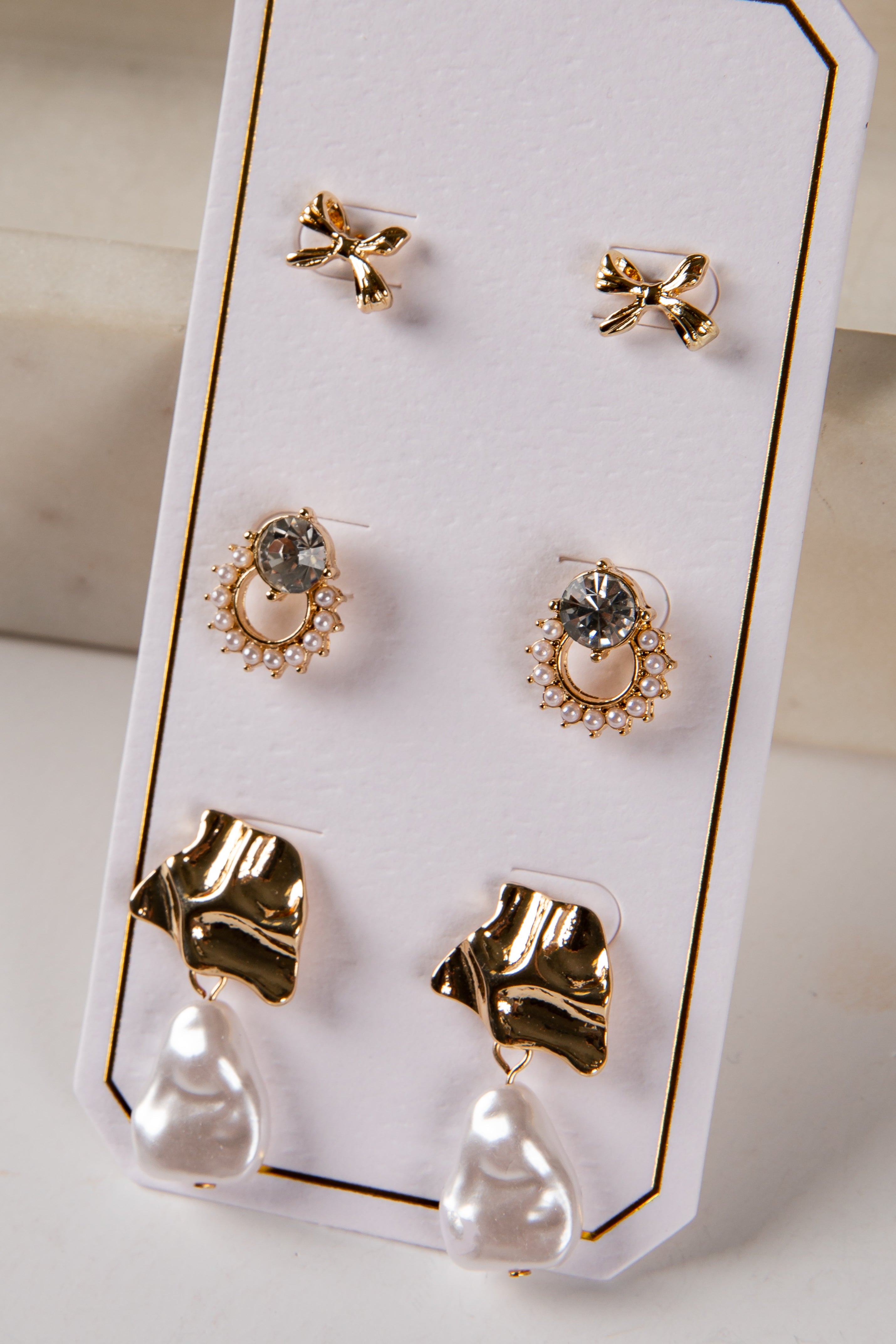 Set of gold and pearl earrings on a display card.