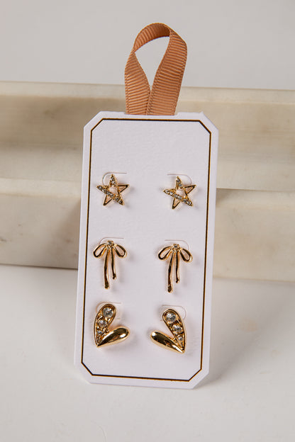 Set of gold earrings on a white card with a brown ribbon