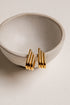 Gold earrings on a beige ceramic bowl