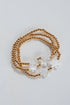 Gold beaded necklace with white floral pendants on a light gray background