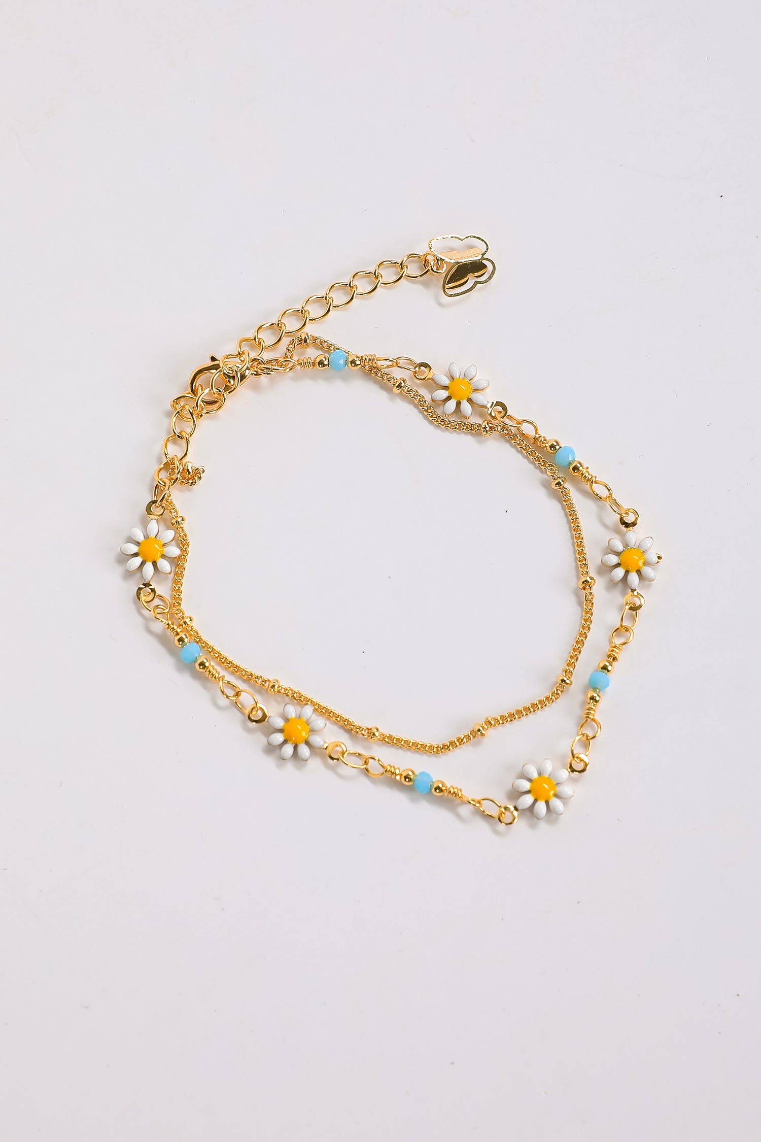 Gold chain bracelet with floral charms on a light gray background