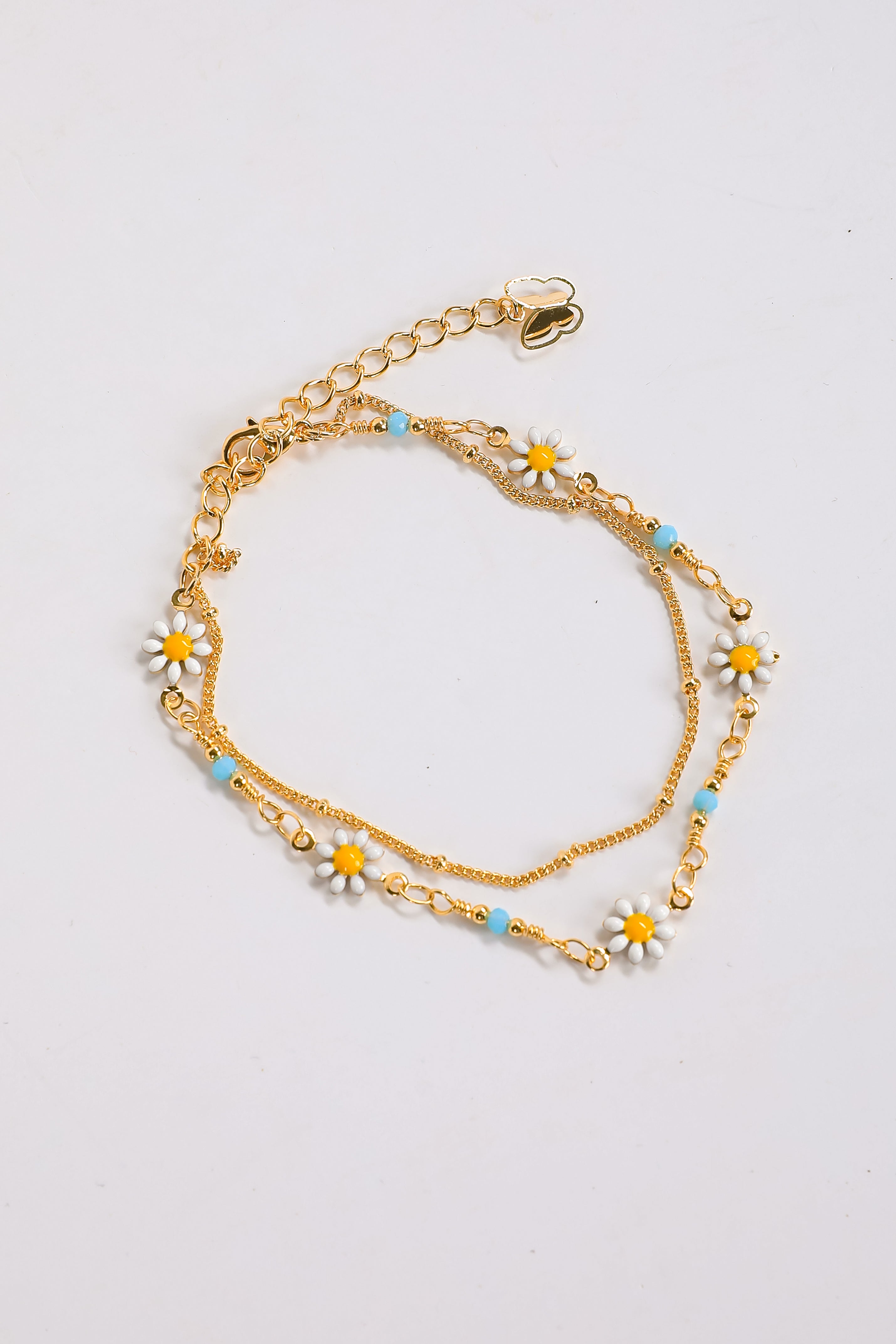 Gold chain bracelet with floral charms on a light gray background