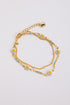 Gold chain bracelet with floral charms on a light gray background
