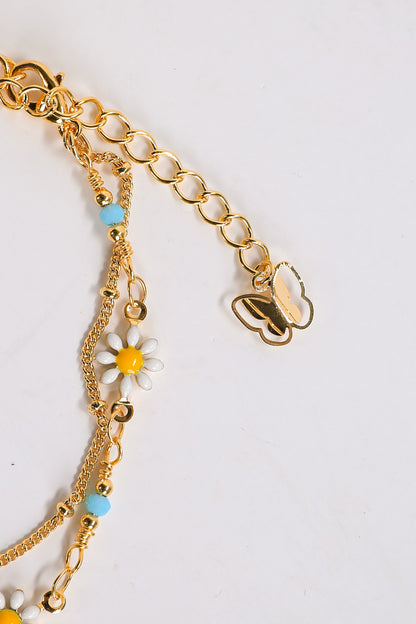 Gold bracelet with floral charms on a light gray background
