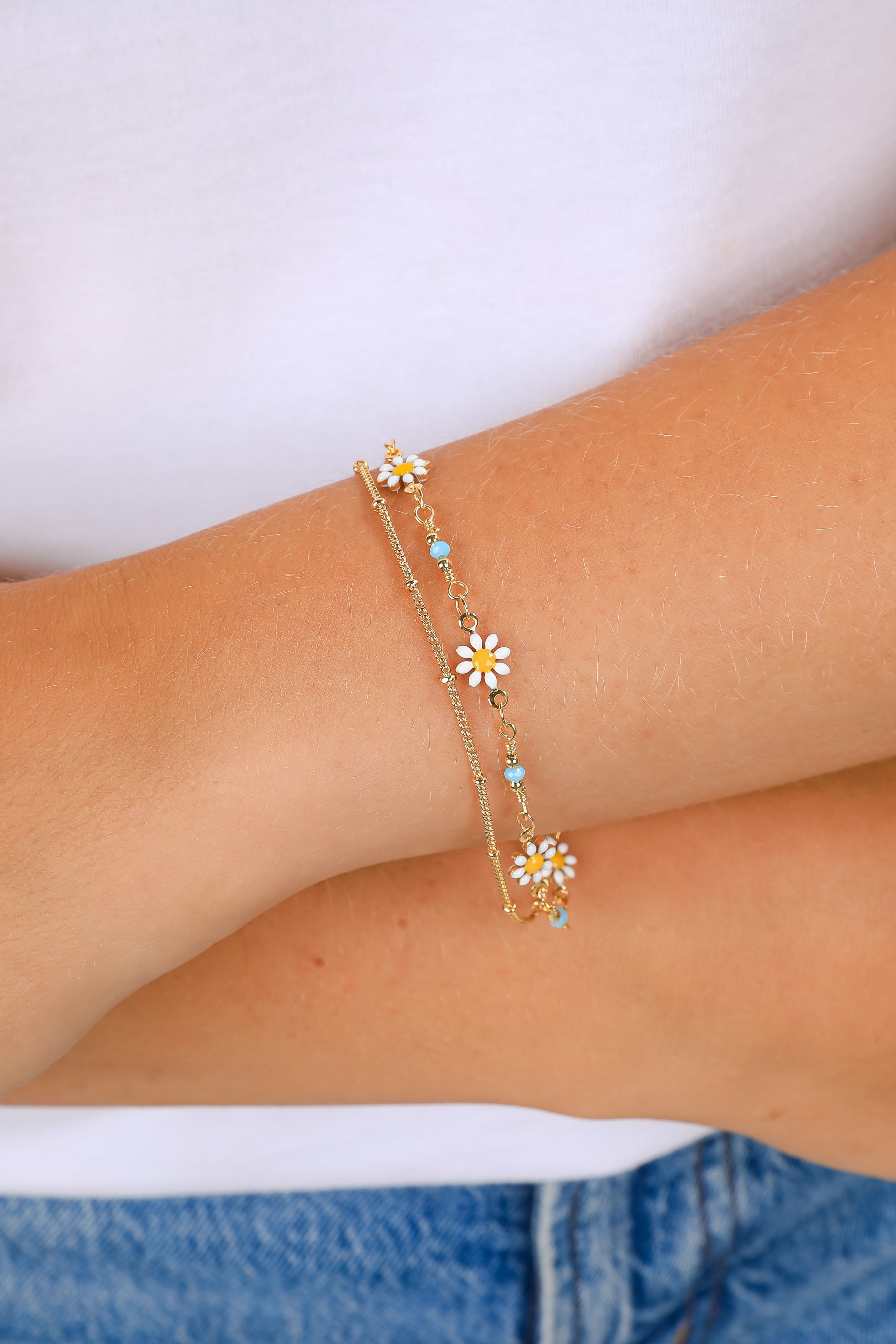 Bracelet with floral charms on a wrist against a white background