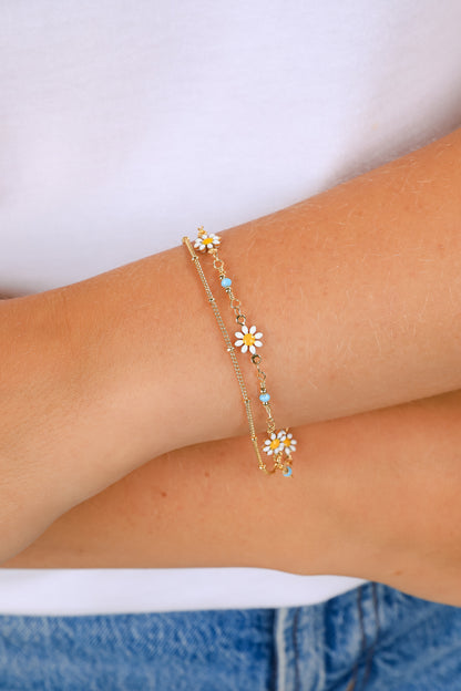 Bracelet with floral charms on a wrist against a white background