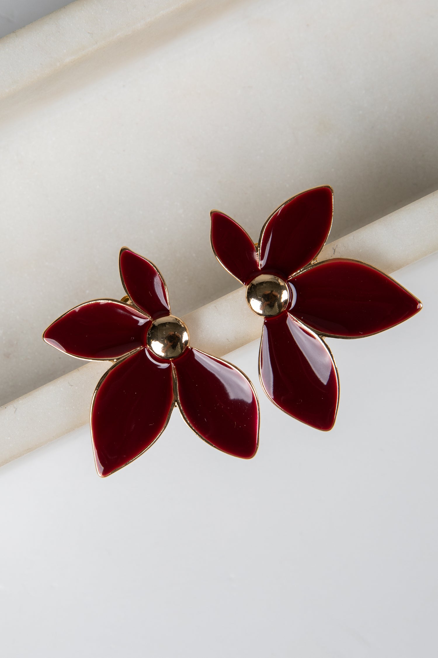 Red flower-shaped earrings with gold centers on a white background