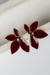 Red flower-shaped earrings with gold centers on a white background