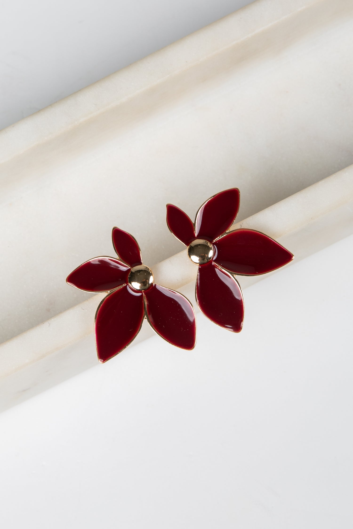 Red flower-shaped earrings on a white surface