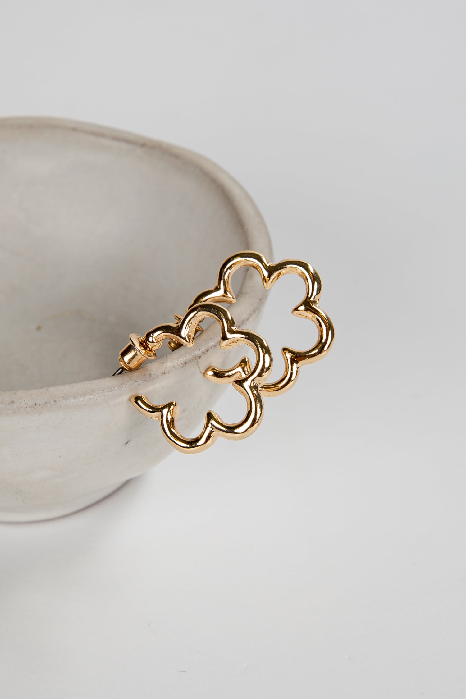 Gold chain earring on a white ceramic dish