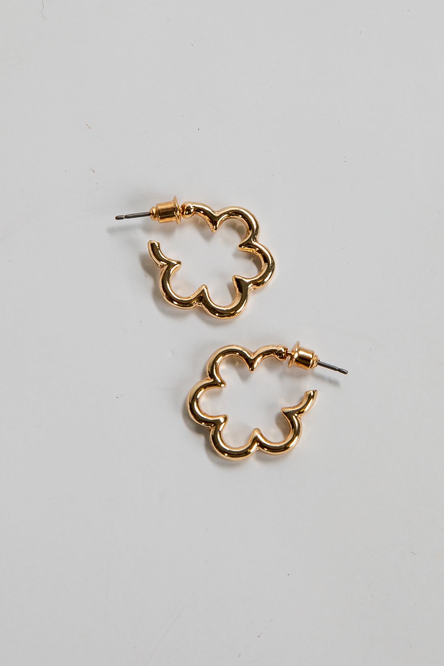 Gold clover-shaped earrings on a light gray background