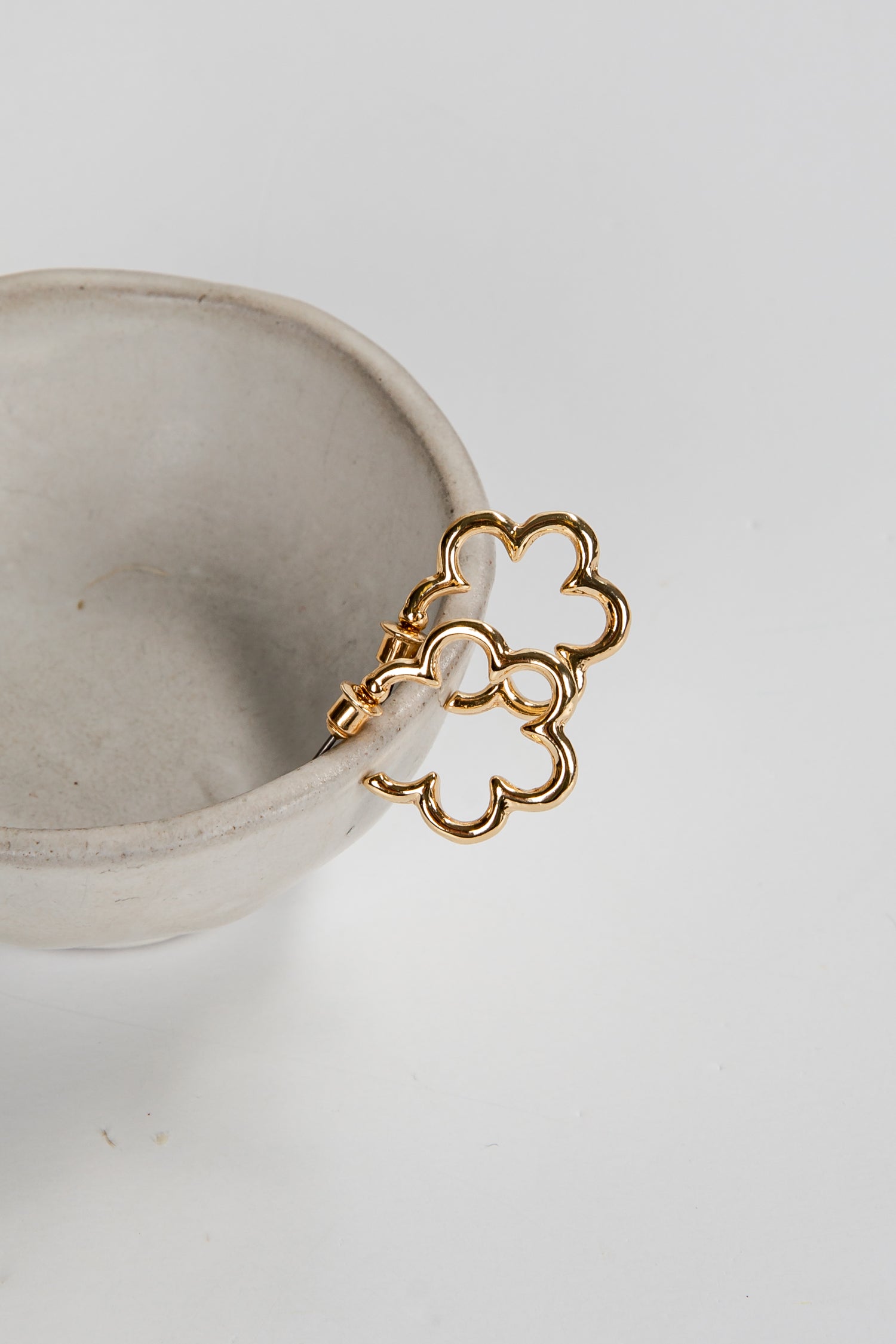 Gold bracelet on a white ceramic cup against a light gray background