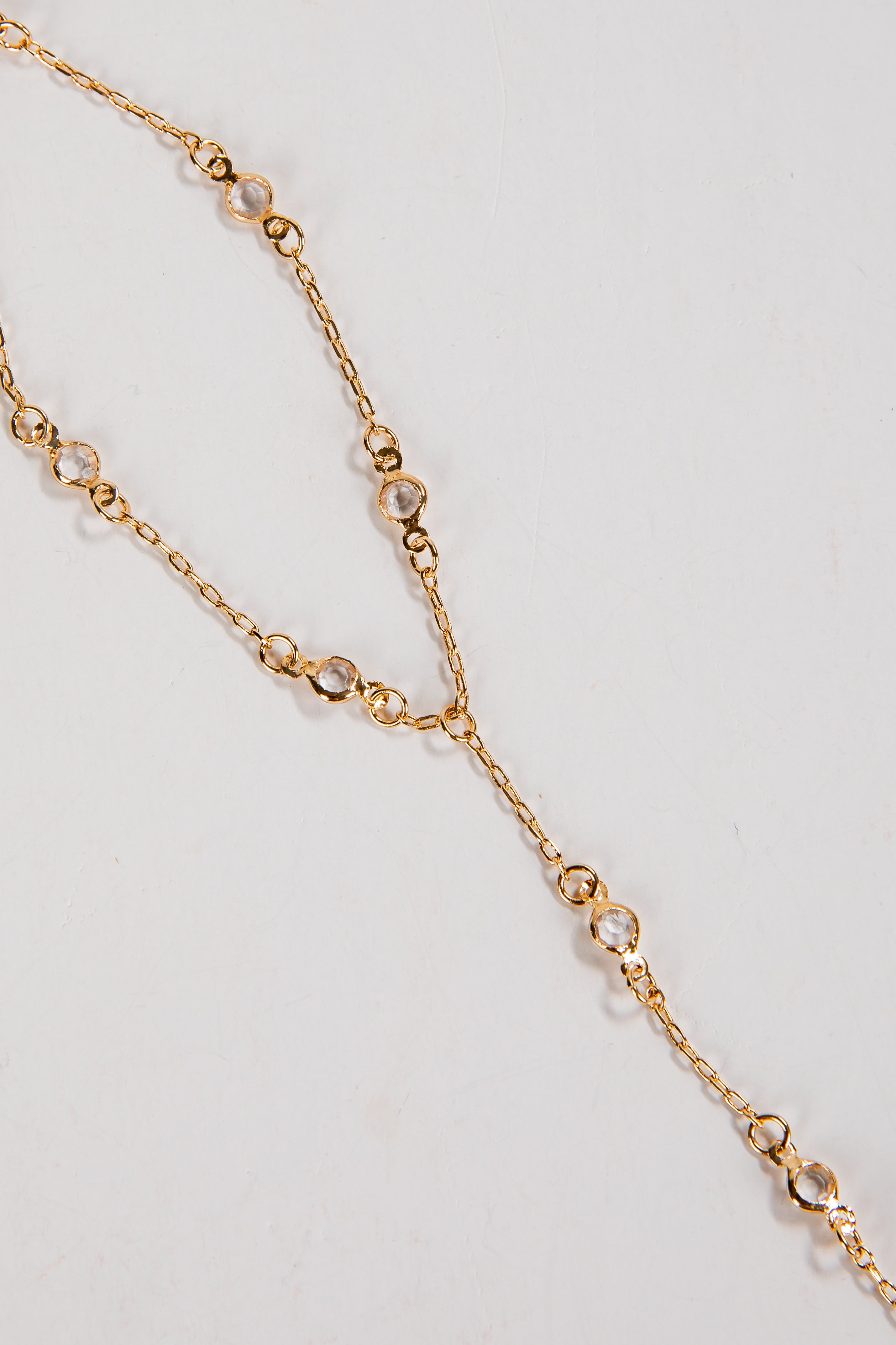 Gold chain necklace with small beads on a light gray background