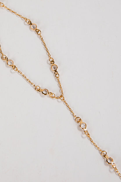 Gold chain necklace with small beads on a light gray background