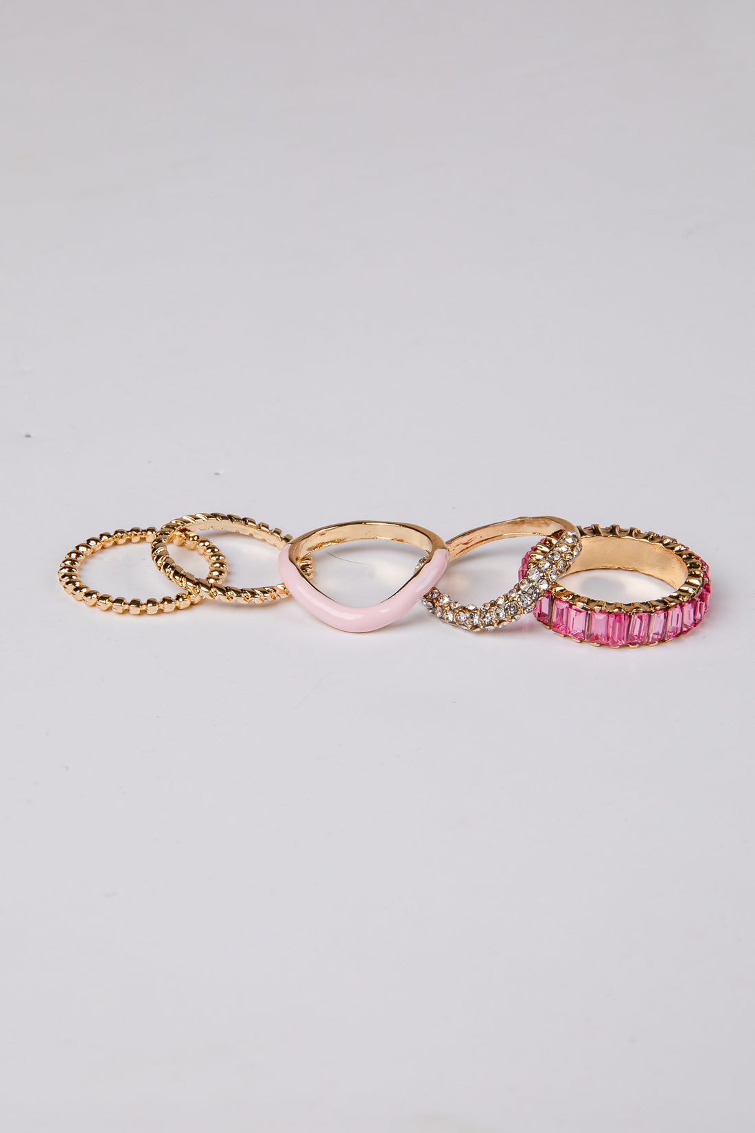Set of five gold and pink rings on a light gray background