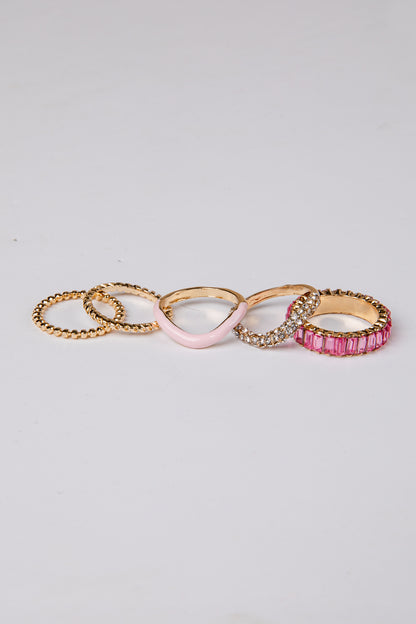 Set of five gold and pink rings on a light gray background