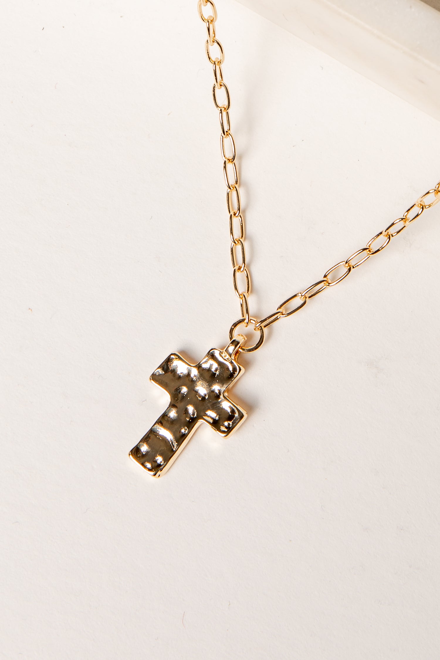 Gold cross necklace on a white background