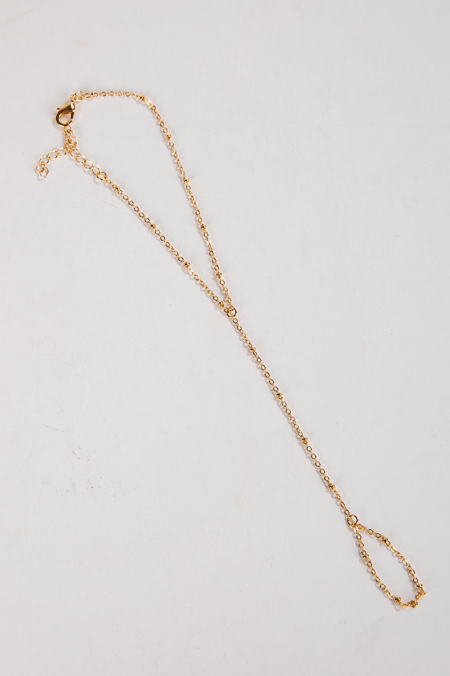 Gold necklace on a light gray background