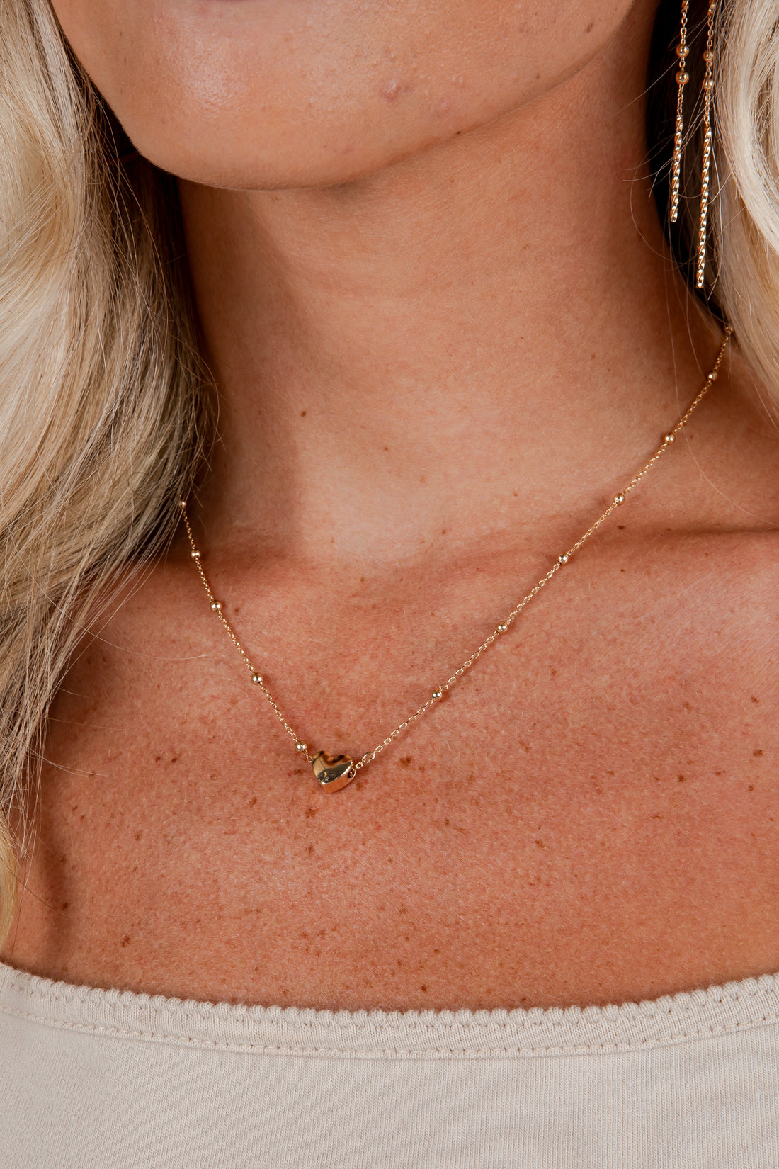 Close-up of a person wearing a delicate gold necklace with a small pendant.