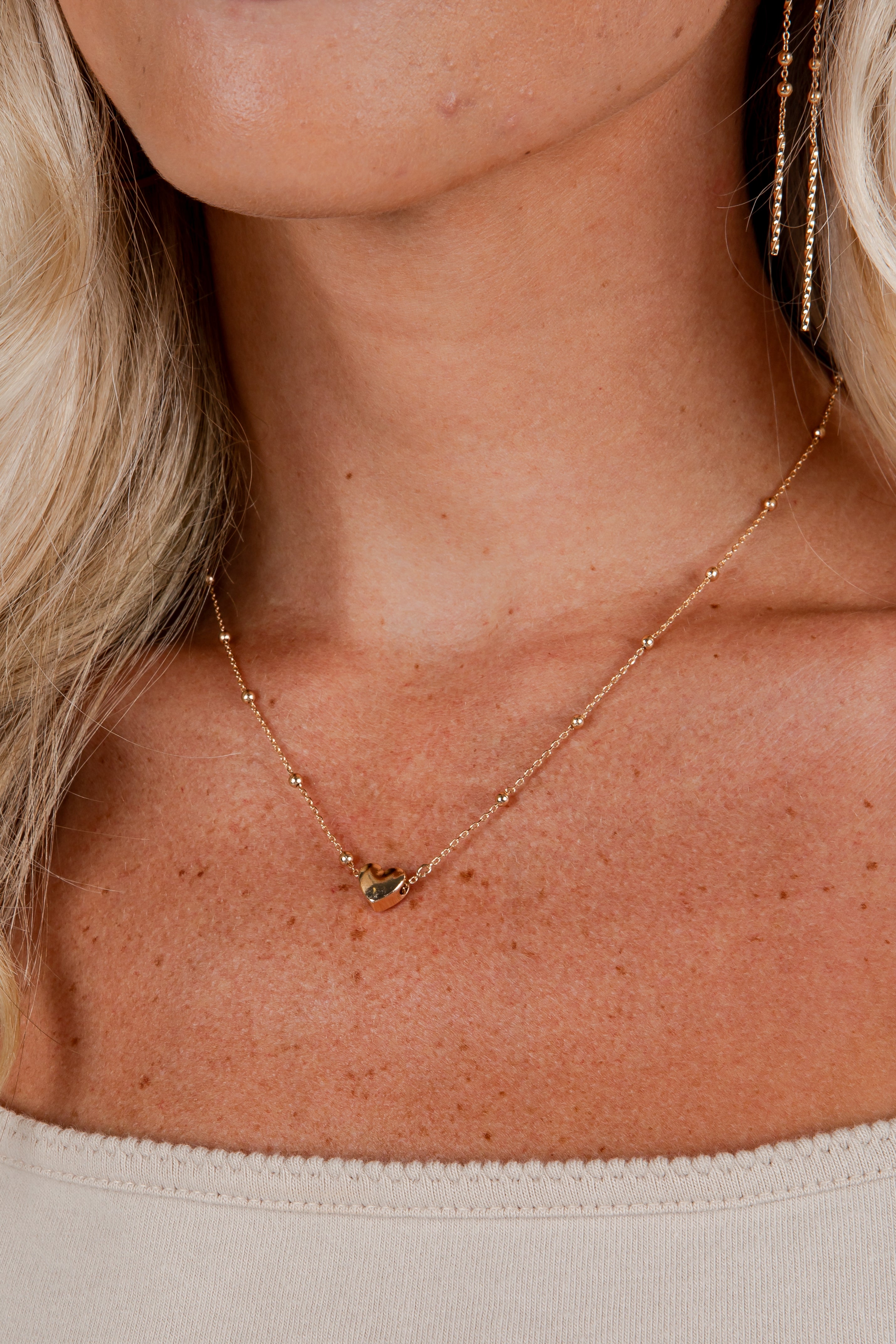 Close-up of a person wearing a delicate gold necklace with a small pendant.