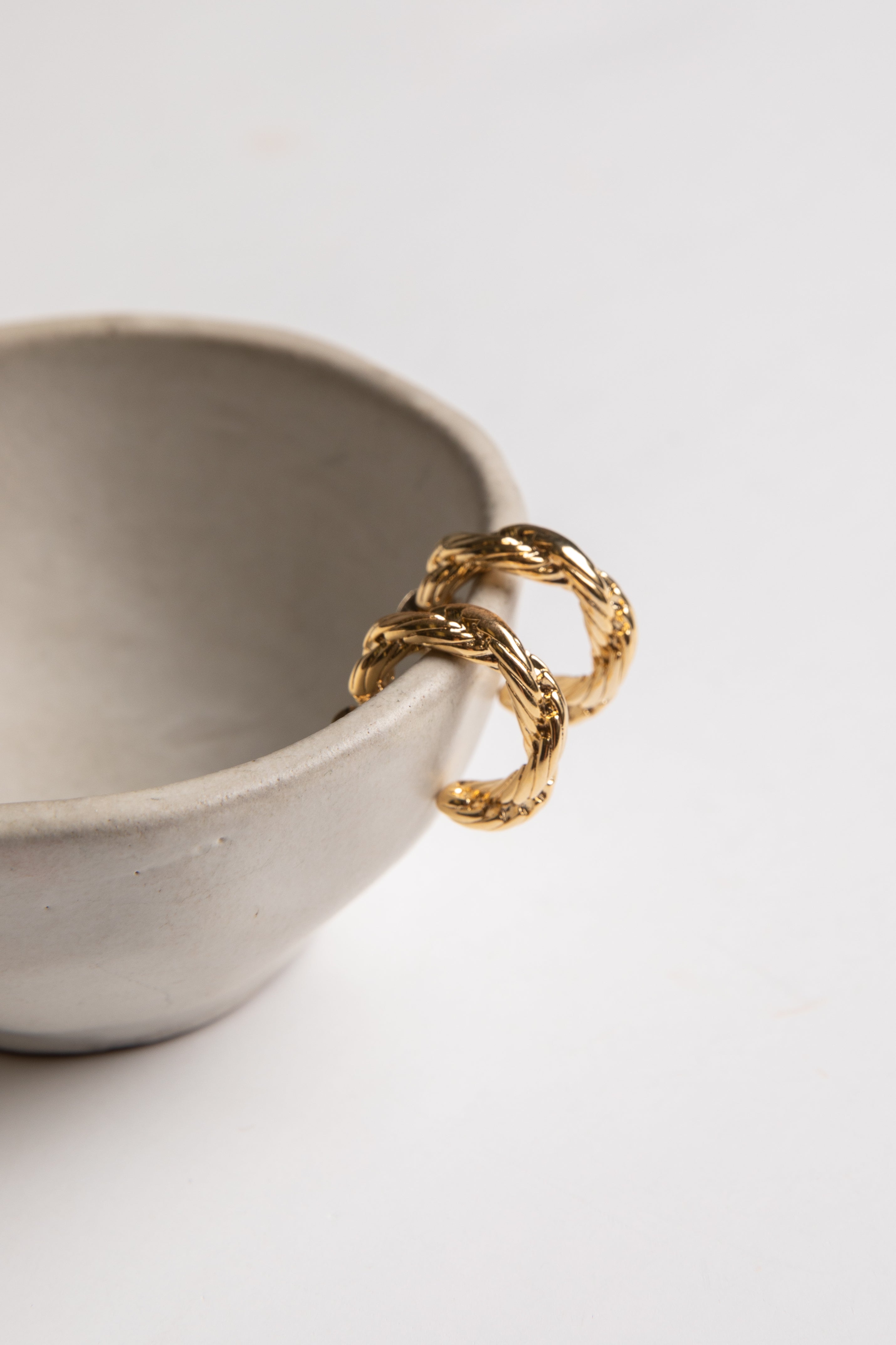 Gold ring on a gray ceramic bowl against a light gray background