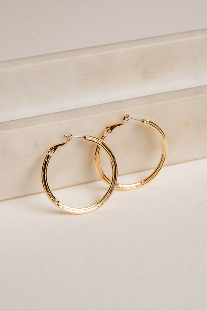 Gold hoop earrings on a light beige surface
